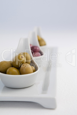 Close up of brown and green olives in white containers