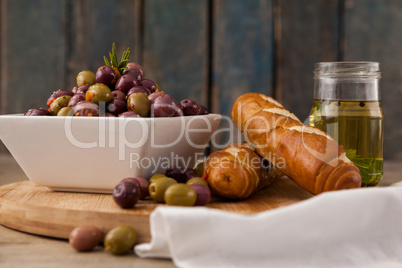 Olives in container by bread and oil
