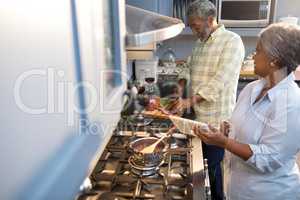 Woman showing tablet computer to man while preparing food