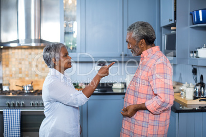 Side view of displeased couple standing in kitchen