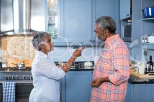 Side view of displeased couple standing in kitchen
