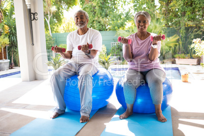 Portrait of senior couple lifting dumbbells