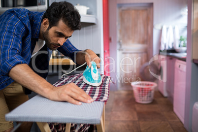 Young man ironing shirt