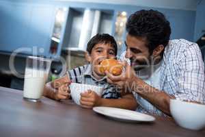 Man feeding croissant to son