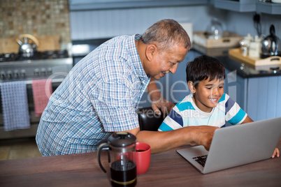 High angle view of grandfather assisting grandson using laptop
