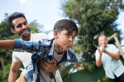 Grandfather looking at man playing with son