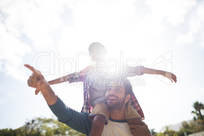 Happy father gesturing while carrying son on shoulder