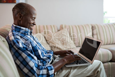 Side view of smiling man using laptop