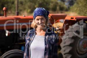 Portrait of happy woman standing against tractor in olive farm