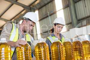 Workers checking records of oil bottles