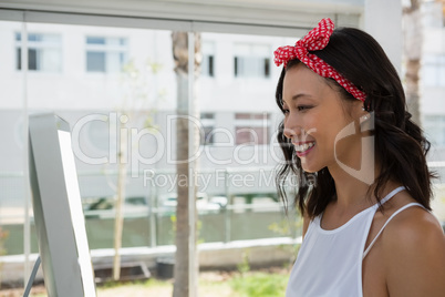 Smiling businesswoman using computer by window in office