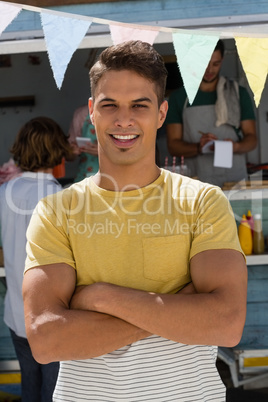 Man with arms crossed standing by food truck