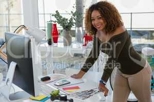 Smiling businesswoman standing at desk in office