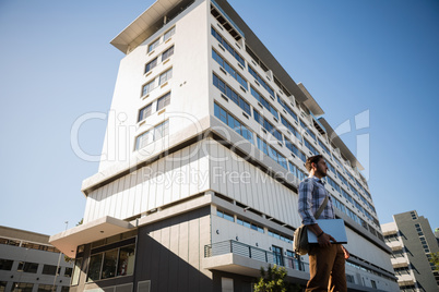 Man holding laptop while standing by building in city