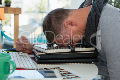 Frustrated man sleeping on files in office