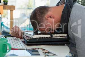 Frustrated man sleeping on files in office