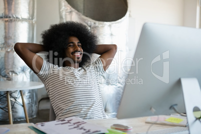 Smiling young man relaxing at desk in office