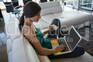 Woman using laptop while relaxing on sofa at office