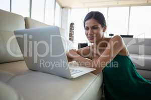 Young businesswoman using laptop on sofa at office