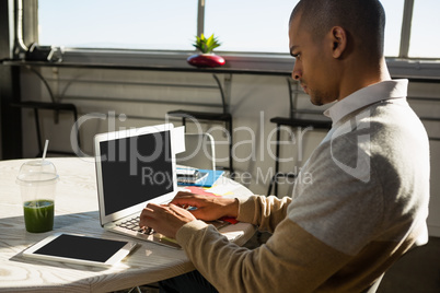 Concentrated man using laptop at office