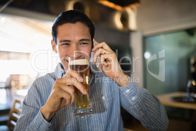 Man having beer while talking on mobile phone