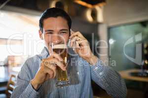 Man having beer while talking on mobile phone