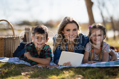 Mother and kids holding digital tablet in park