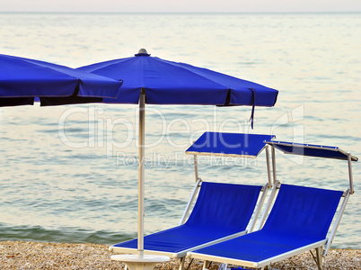 two sunbeds on a stony beach