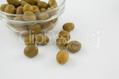 Close up of green olives by glass bowl on table