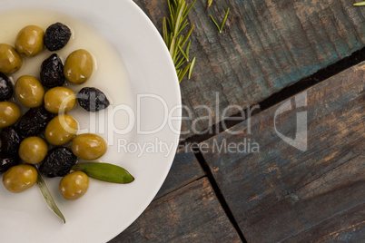 Overhead view of green and dry black olives with oil in plate