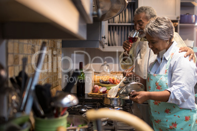 Man having wine while woman preparing food