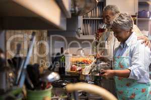 Man having wine while woman preparing food