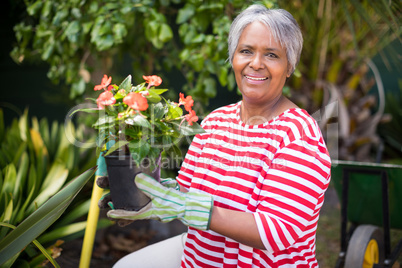 Portrait of smiling woman holding potted plant