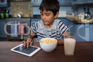 Boy using tablet computer while having breakfast