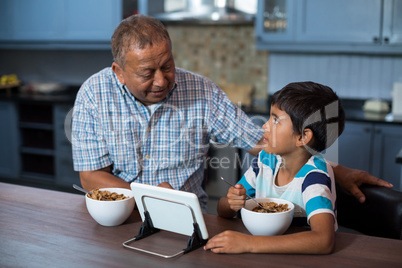 Grandfather and grandson using tablet computer during breakfast