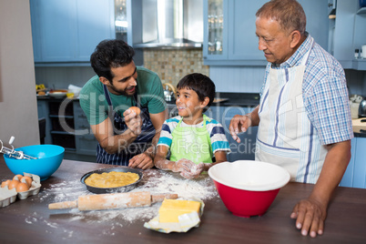 Man showing egg to boy standing by grandfather