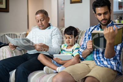 Boy with grandfather and father sitting on sofa