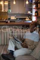 Man reading newspaper while sitting on sofa