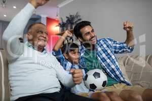 Happy family with arms raised watching soccer match