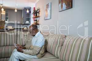 Side view of happy senior man using tablet