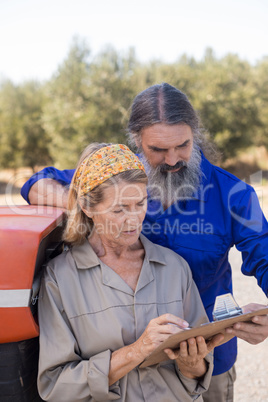 Couple discussing over clipboard in olive farm