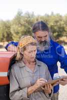 Couple discussing over clipboard in olive farm