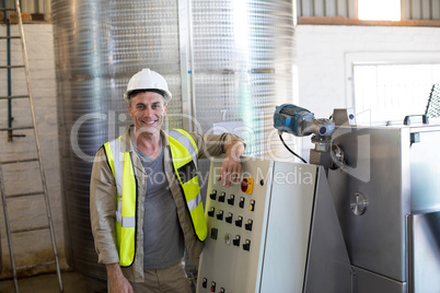 Portrait of happy technician standing near machine