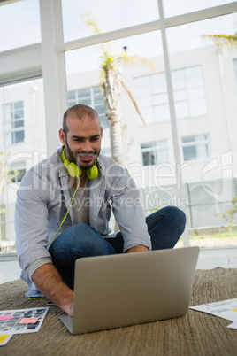 Designer using laptop while sitting on floor