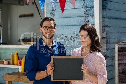 Coworkers holding writing slate while standing by food truck