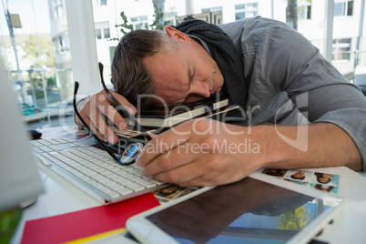 Tired businessman sleeping on files while sitting at desk