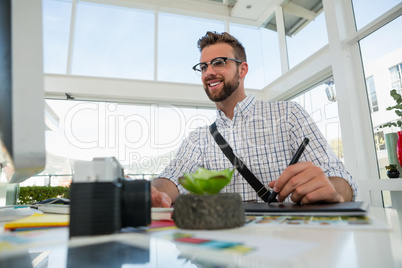 Graphic designer writing on tablet while sitting at desk