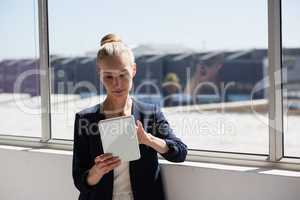 Smiling businesswoman using tablet while standing by window