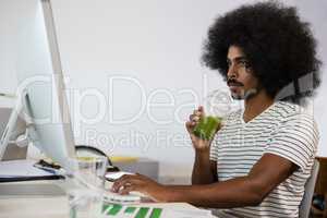 Man having drink while using computer in office