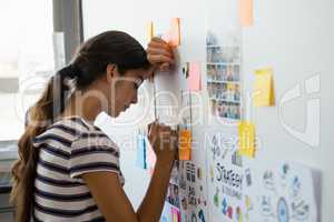 Tired woman leaning on wall with sticky notes in office